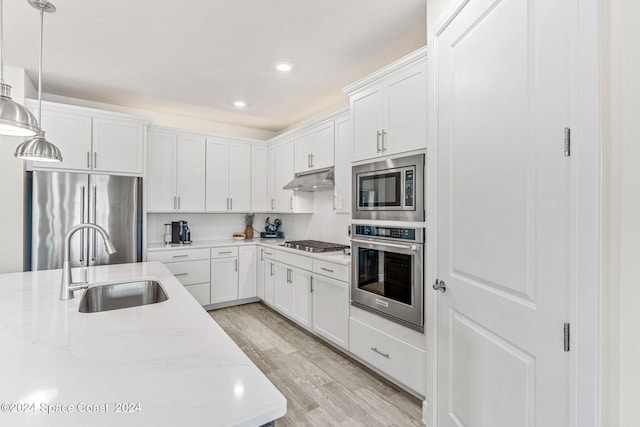 kitchen with pendant lighting, white cabinetry, light hardwood / wood-style floors, and appliances with stainless steel finishes