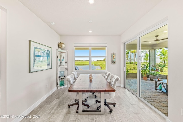 dining area featuring ceiling fan, light wood-type flooring, and a water view