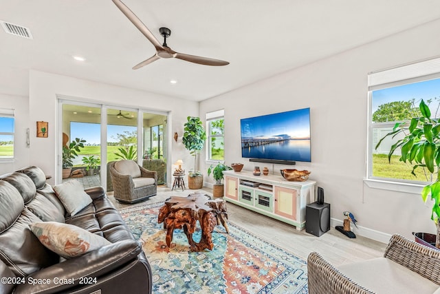 living room with ceiling fan, light wood-type flooring, and plenty of natural light