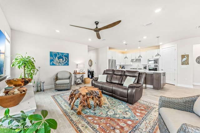 living room with light hardwood / wood-style floors, sink, and ceiling fan