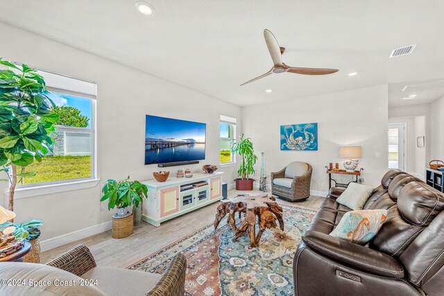 living room with light hardwood / wood-style flooring, ceiling fan, and a healthy amount of sunlight