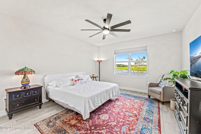 bedroom featuring a textured ceiling, ceiling fan, and light hardwood / wood-style flooring