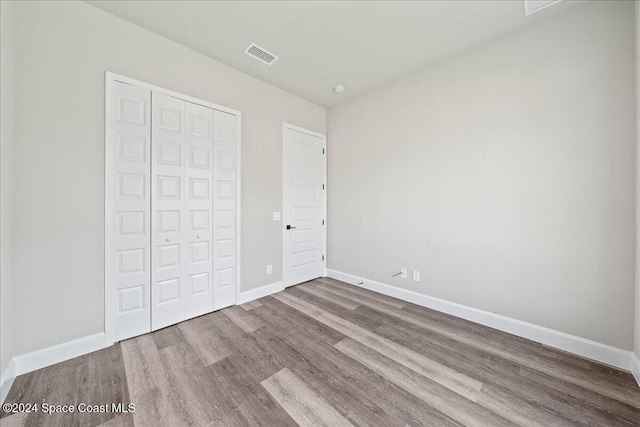 unfurnished bedroom with hardwood / wood-style floors and a closet