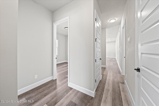 hallway featuring light hardwood / wood-style flooring and a textured ceiling