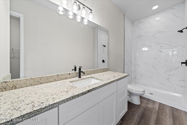 bathroom featuring tiled shower, wood-type flooring, vanity, and toilet