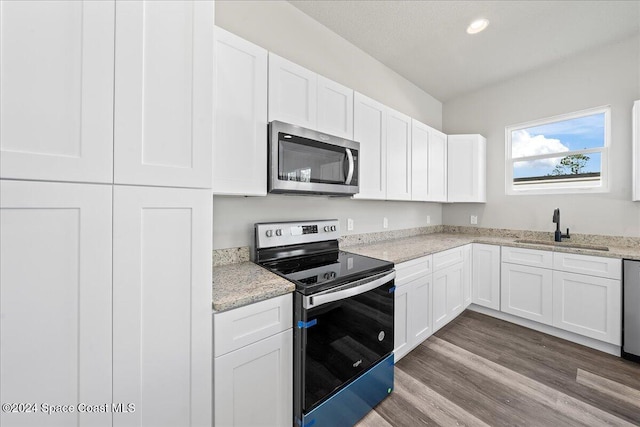 kitchen featuring sink, stainless steel appliances, light stone counters, hardwood / wood-style floors, and white cabinets