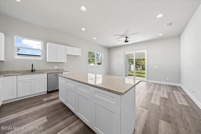 kitchen featuring stainless steel dishwasher, a center island, white cabinets, and light wood-type flooring