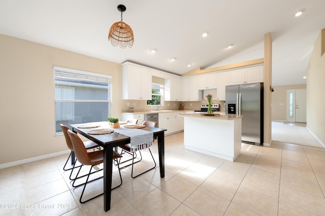 kitchen with appliances with stainless steel finishes, vaulted ceiling, white cabinetry, a kitchen island, and pendant lighting