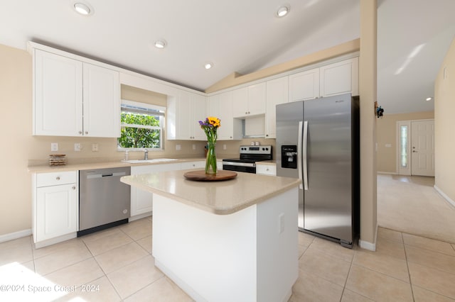 kitchen with appliances with stainless steel finishes, vaulted ceiling, a kitchen island, and white cabinets