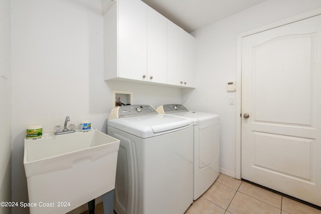 laundry area with washing machine and clothes dryer, cabinets, light tile patterned flooring, and sink