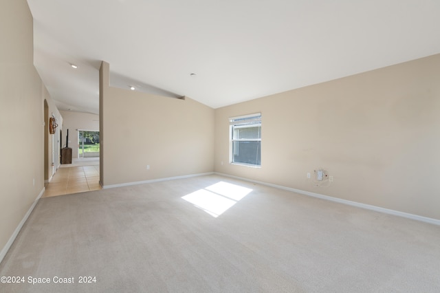 unfurnished room with light colored carpet and vaulted ceiling