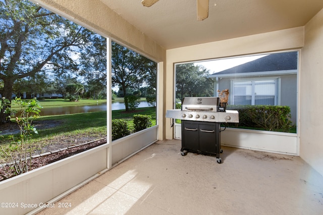 sunroom / solarium featuring a water view and ceiling fan