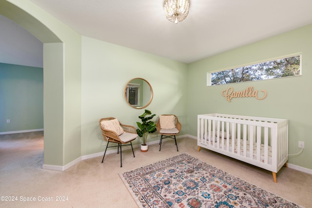 carpeted bedroom featuring a nursery area