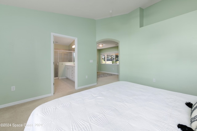 bedroom with light colored carpet and ensuite bath