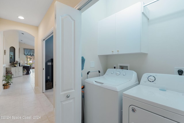 laundry area with separate washer and dryer, cabinets, and light tile patterned floors