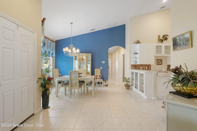 tiled dining space featuring a notable chandelier and high vaulted ceiling