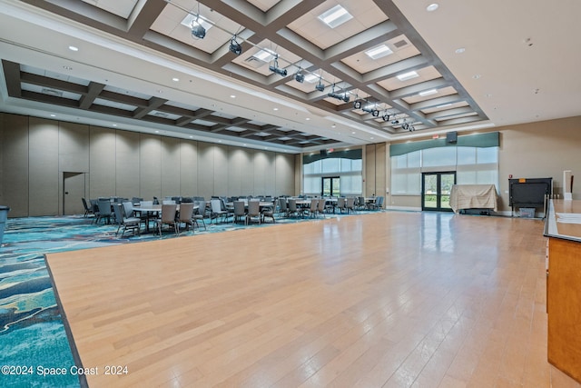 workout area with light wood-type flooring and coffered ceiling