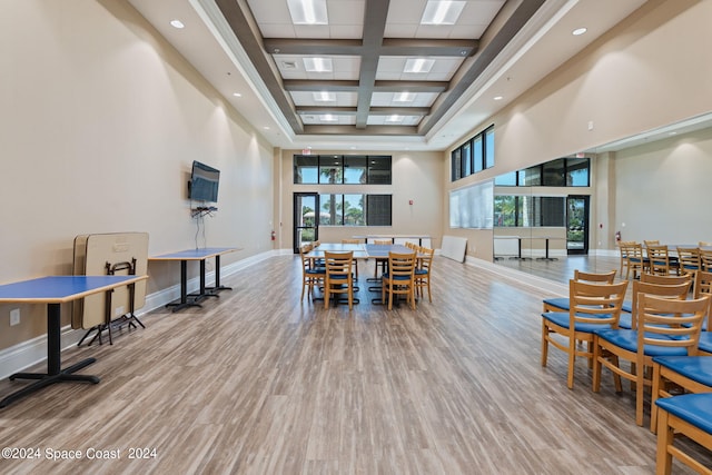 dining space featuring a towering ceiling, hardwood / wood-style flooring, and plenty of natural light