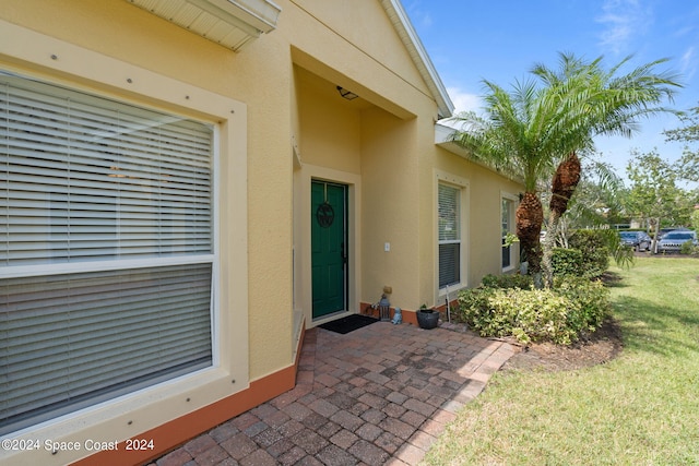 view of exterior entry with a patio and a yard