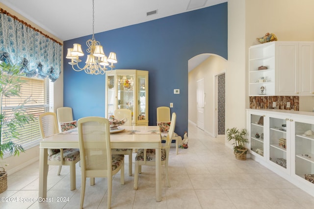 tiled dining room featuring high vaulted ceiling and a chandelier