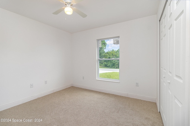 unfurnished bedroom featuring ceiling fan, light colored carpet, and a closet