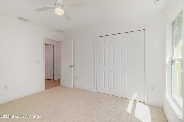 unfurnished bedroom with ceiling fan, light colored carpet, and multiple windows