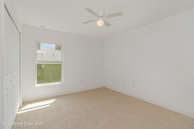 spare room with ceiling fan and light colored carpet