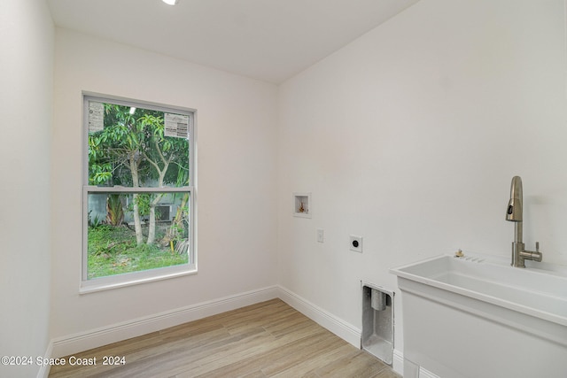 washroom with light hardwood / wood-style flooring, hookup for an electric dryer, hookup for a washing machine, and sink