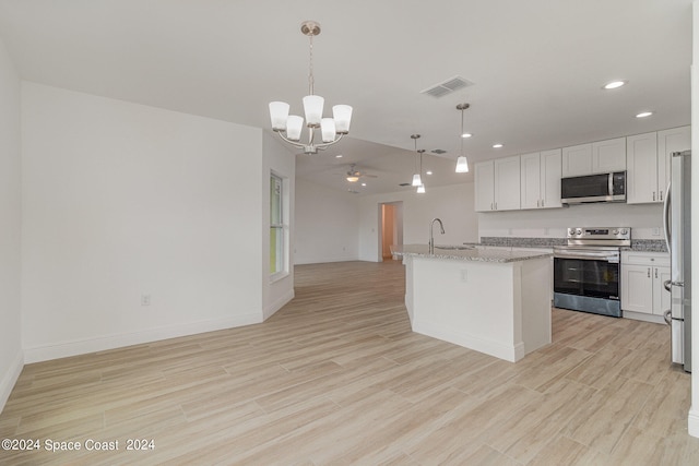 kitchen featuring light wood-type flooring, an island with sink, white cabinets, stainless steel appliances, and decorative light fixtures