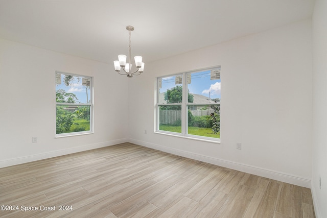 spare room featuring a notable chandelier and light hardwood / wood-style floors