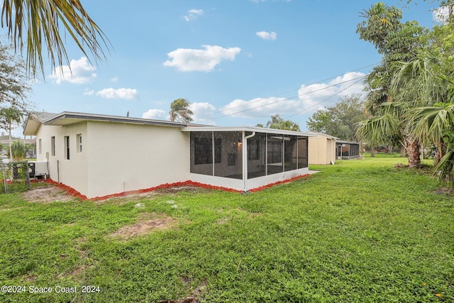 rear view of house featuring a sunroom and a lawn