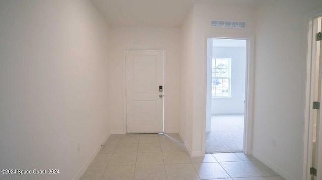 corridor featuring light tile patterned floors, visible vents, and baseboards
