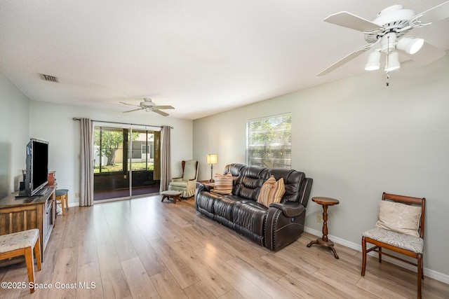 living room with baseboards, visible vents, light wood finished floors, and ceiling fan