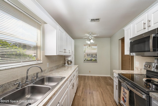 kitchen with a sink, visible vents, appliances with stainless steel finishes, and white cabinets