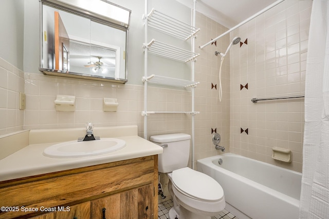 full bath with toilet, vanity, shower / tub combo, tile walls, and a ceiling fan