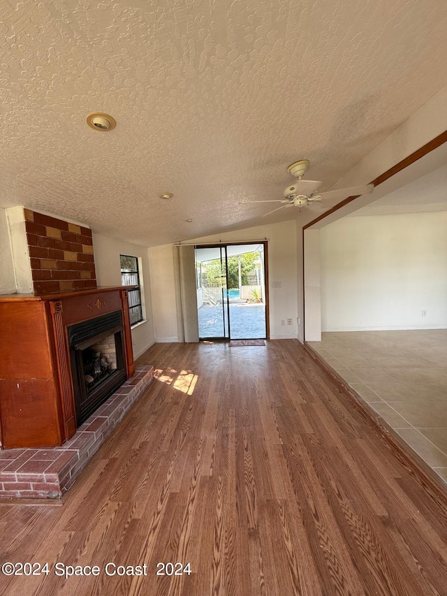 unfurnished living room featuring ceiling fan, hardwood / wood-style flooring, a fireplace, and a textured ceiling