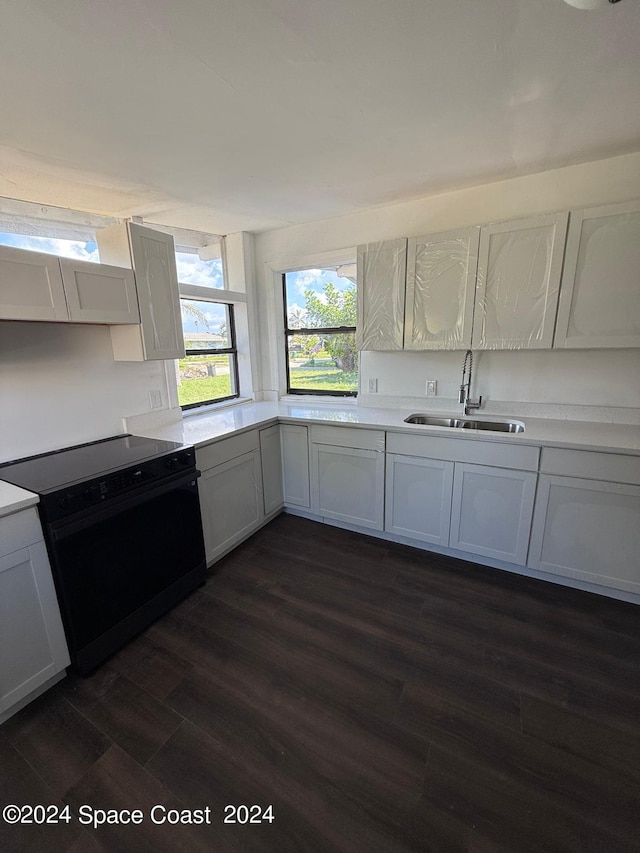 kitchen featuring black range with electric stovetop, white cabinets, dark wood-type flooring, and sink