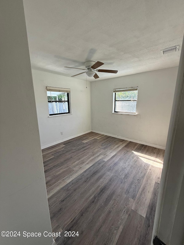 unfurnished room with ceiling fan, a textured ceiling, and dark wood-type flooring