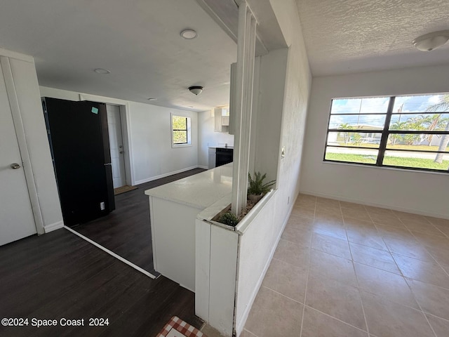 kitchen with a textured ceiling, hardwood / wood-style flooring, plenty of natural light, and white cabinets