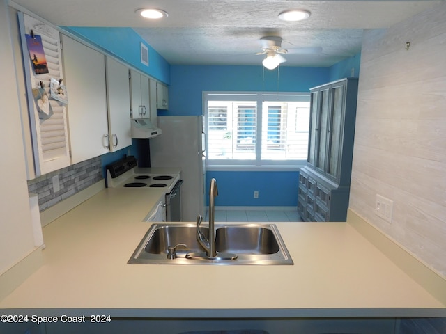 kitchen with white appliances, a ceiling fan, under cabinet range hood, light countertops, and a sink