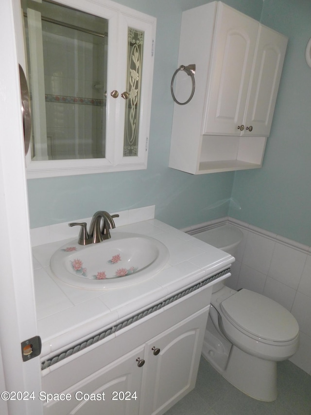 bathroom with tile walls, vanity, and toilet