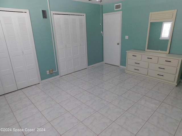 unfurnished bedroom with multiple closets and light tile patterned floors