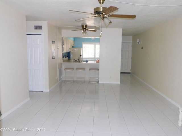 living area featuring light tile patterned floors, visible vents, and ceiling fan