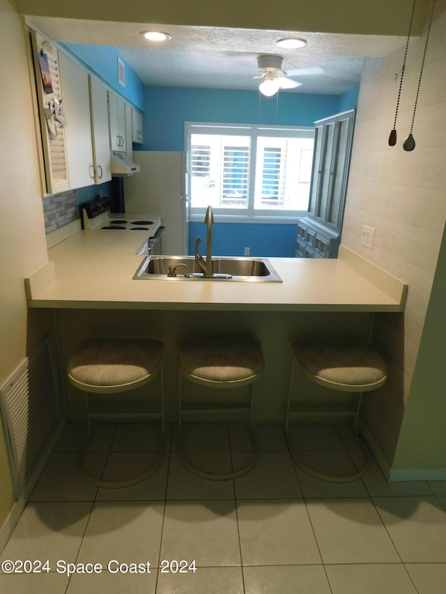 kitchen with electric stove, light tile patterned floors, range hood, ceiling fan, and sink