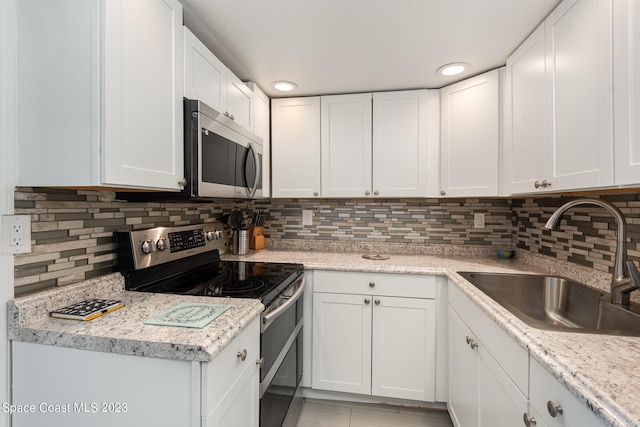 kitchen with backsplash, stainless steel appliances, sink, and white cabinets