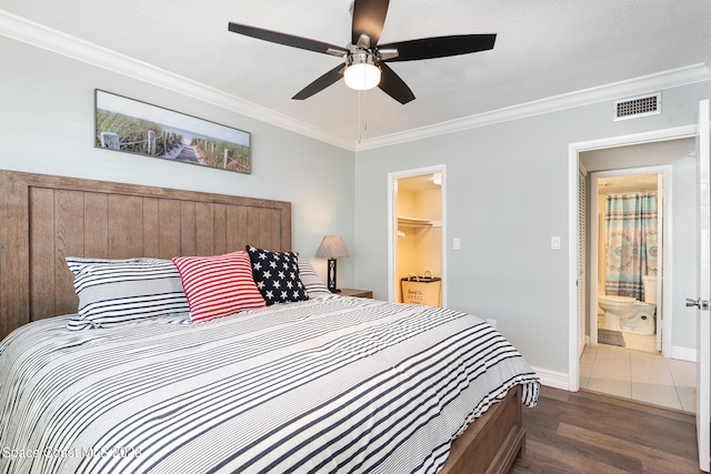 bedroom with a closet, dark wood-type flooring, a spacious closet, ensuite bathroom, and ceiling fan