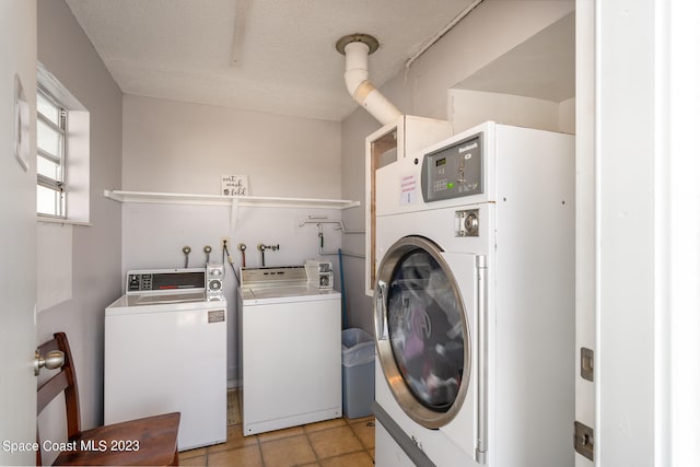 laundry area with a textured ceiling, light tile patterned flooring, and washing machine and clothes dryer