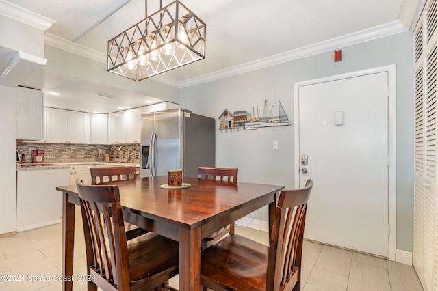 tiled dining room with ornamental molding, a chandelier, and sink