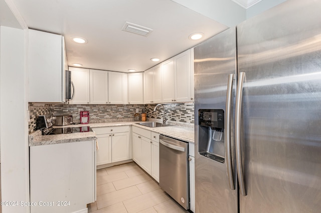 kitchen featuring sink, backsplash, white cabinetry, stainless steel appliances, and light stone counters