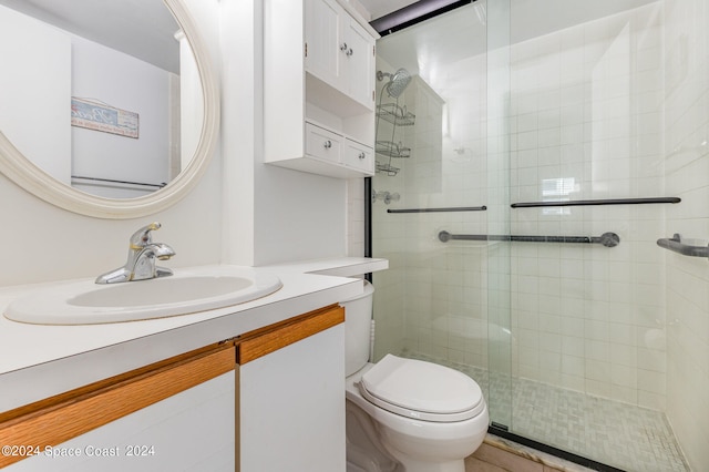 bathroom featuring toilet, a shower with shower door, and vanity